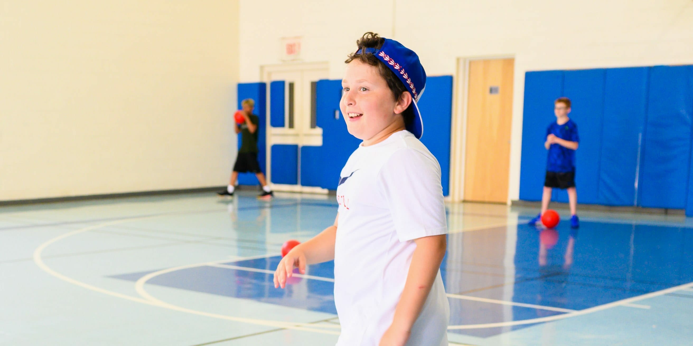 Young camper playing basketball indoors
