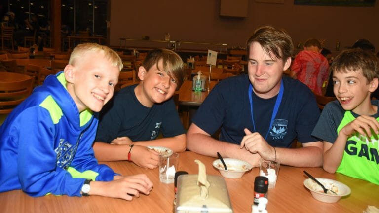 Campers and staff in the dining hall finishing a meal