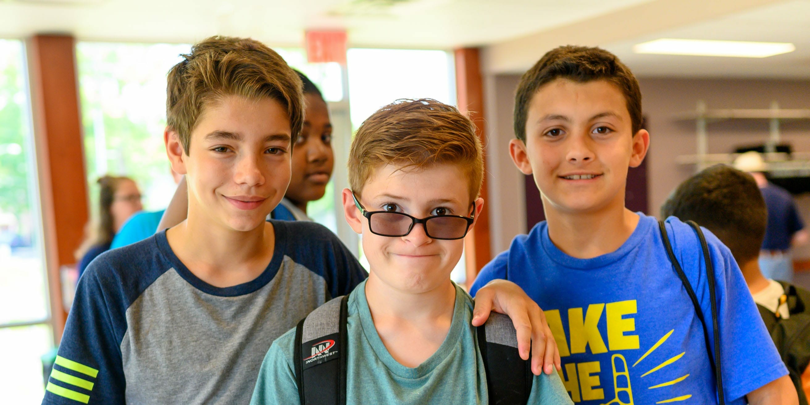 Three boys smiling by dining hall
